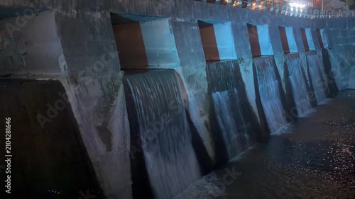 Video footage of a hydroelectric dam with flowing water, captured in a dramatic industrial setting.