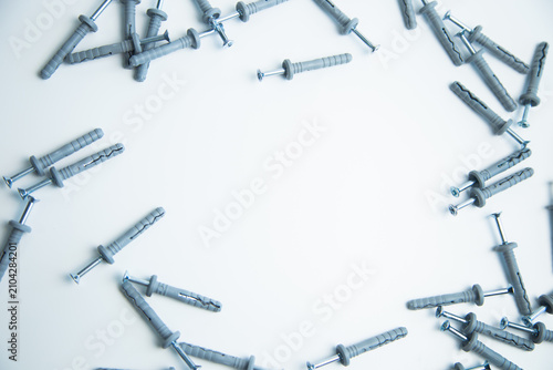 A top view of the self-tapping screws with dopes, which lie on the sides on a white background with free space in the center for text. The concept of repair, screwing, fixing, construction. High