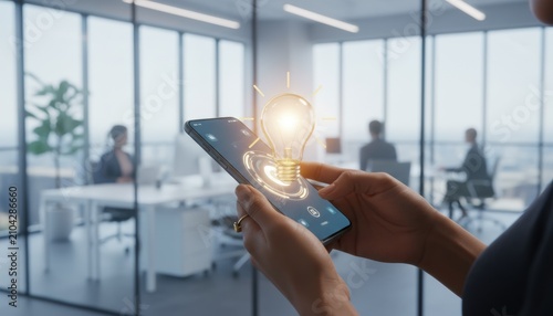 Innovative Idea on Mobile: A close-up of a person holding a smartphone displaying a glowing lightbulb icon, symbolizing innovation and new ideas, with a blurred modern office background.
