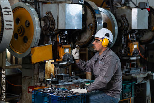 Фотография A white male factory worker in workwear,hard hat,protective glasses and earmuffs