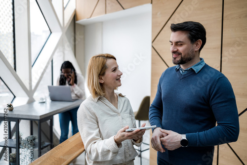Two people talk while another uses a laptop at a modern office