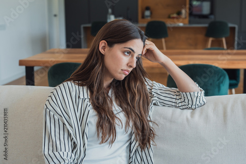 Foto Young woman sitting on a comfortable sofa in her living room, experiencing feeli