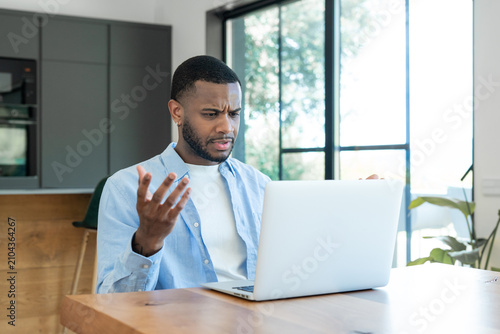 Εκτύπωση καμβά Young man experiencing frustration and confusion while looking at a laptop, gest