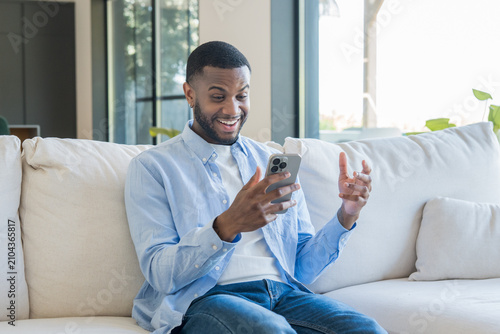 Obraz na plátně Young african american man feeling excited and joyful during a video call on his