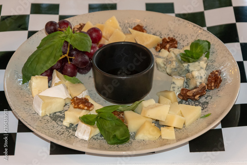 Assorted cheese platter with grapes walnuts basil and dipping sauce served for gourmet restaurant dining