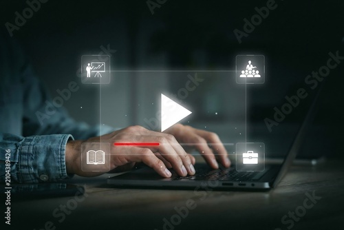 Person using a laptop to access online education and e-learning video training courses at home