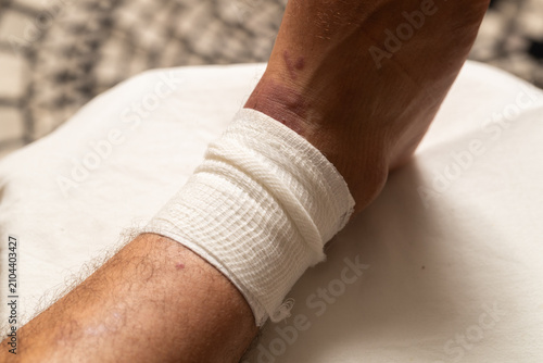 Macro close-up of a white gauze bandage wrapped around a patient's leg and ankle