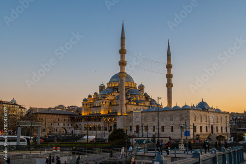 Photography Illuminated New Mosque (Yeni Camii) at sunset, view from Galata Bridge in Istanbul, Turkey