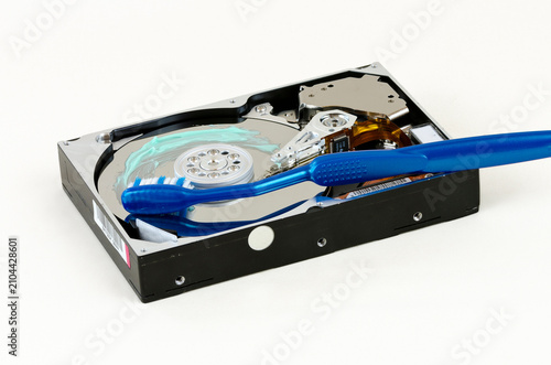 symbolic depiction of cleaning an opened harddisc with blue toothbrush and toothpaste