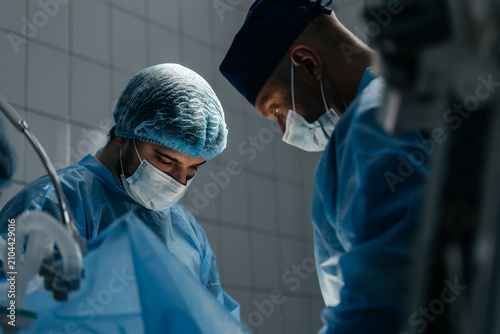 фотографія Surgical team performing medical procedure under operating lights in a modern ho