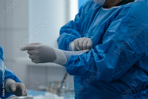 Canvas Print Surgeon putting on sterile surgical gloves before an operation in a modern hospi