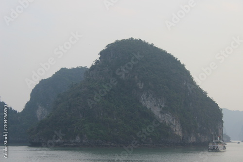 Scenic karst limestone mountain landscape rising above emerald sea of ha long bay.