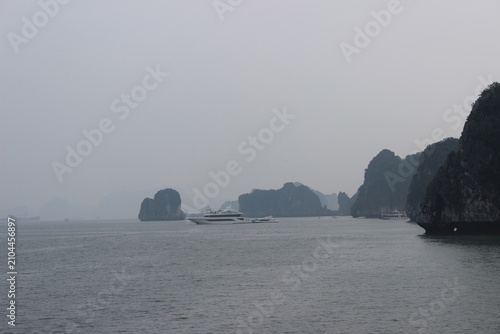 Cruise ships sailing near towering limestone mountain islands in ha long bay area.
