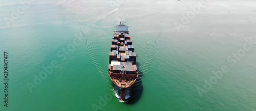 Large Oil tanker ship navigates bustling harbor alongside container ships at Port of Singapore, showcasing vital maritime transport and global trade infrastructure beneath clear sky.