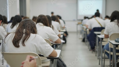 Students sitting in rows taking an exam in a large classroom or lecture hall