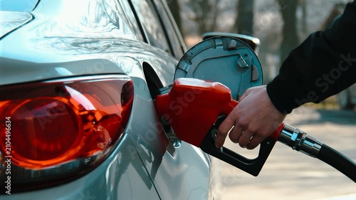 Cuadro en lienzo Fueling a car at a gas station, close-up of a man's hand holding a fuel nozzle at the gas tank