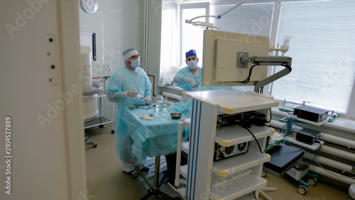 Obraz na płótnie Surgical team preparing sterile instruments beside operating table in bright cli