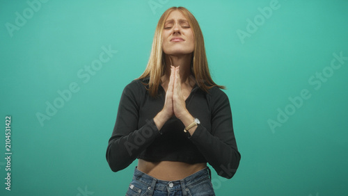 Fotografie Woman pressing hands together in prayer with clasped palms and jeans in a studio; calm hope gratitude