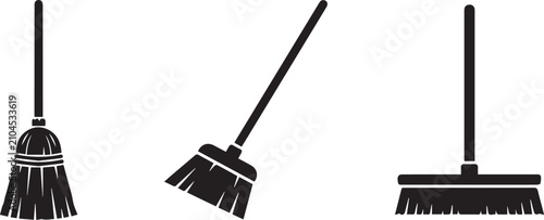 Three black push brooms with wooden handles for cleaning. Essential janitorial tools for sweeping floors and outdoor maintenance.
