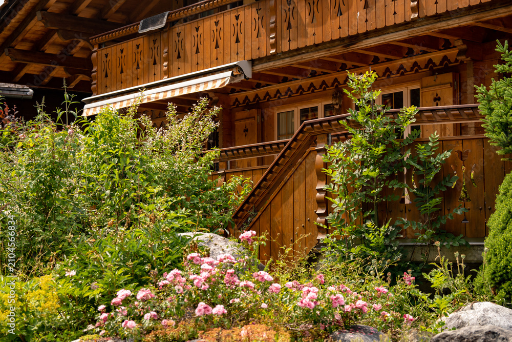 Obraz premium Traditional Swiss chalet wooden house facade close up with blooming summer flower garden in Grindelwald village, alpine Europe