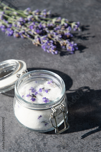 Lavender sugar in glass jar with blurred lavender bouquet, vertical