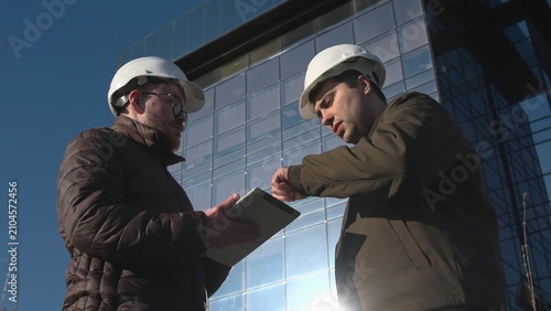 Professionals In Safety Helmets Discuss Architectural Plans And Approve Inspection Procedures At Site. Media