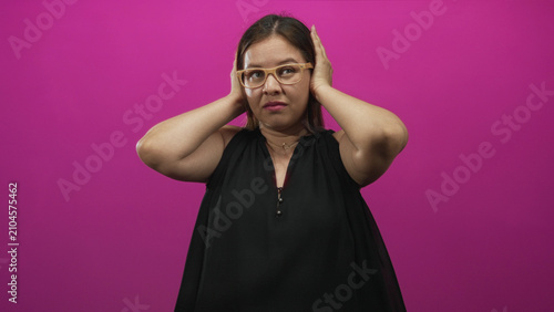 Foto Woman young caucasian covering ears with hands and raised arms in a bright magenta studio; annoyance isolation