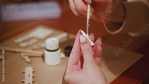 Foto Hands applying white glue with fine paintbrush to small unfinished wooden model