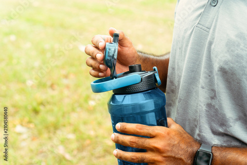 фотографія Man opening water bottle hydrating during physical activity