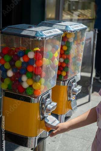 A gumball machine containing colorful round gumballs