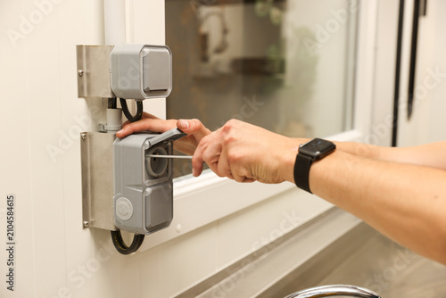 Photography Electrician installing weatherproof outdoor electrical outlet with screwdriver i