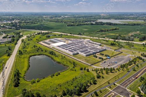 Aerial view of a modern data center facility with solar panels on the roof, cooling units and server buildings