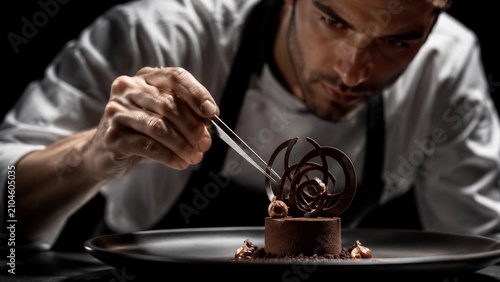 Chef delicately decorating chocolate dessert on black plate