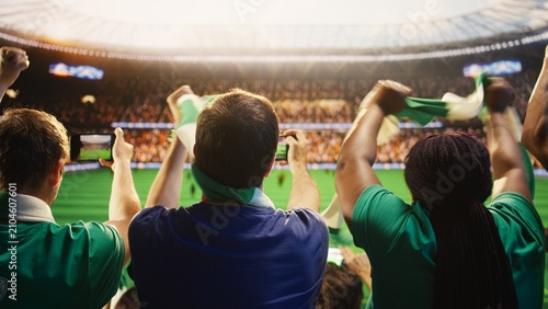 Tableau sur toile Soccer fans use smartphones to record a football match from stadium stands, filming players on the field while joining crowd chants and sharing the live sports experience with other supporters