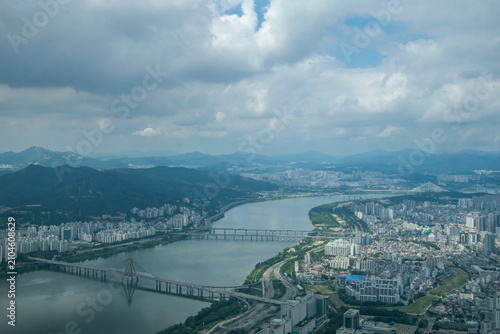 Aerial Seoul river and dense skyline with mountain backdrop viewed from Seoul Sky Lotte World Tower