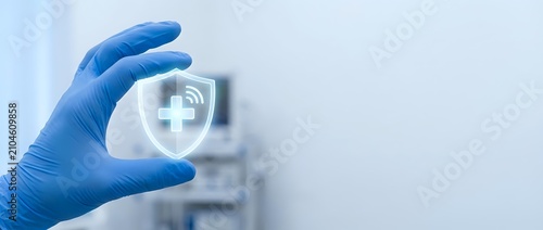 Young adult healthcare professional wearing blue latex glove holding digital medical cross icon with wireless connectivity symbol for telemedicine, digital health, and remote patient care services.