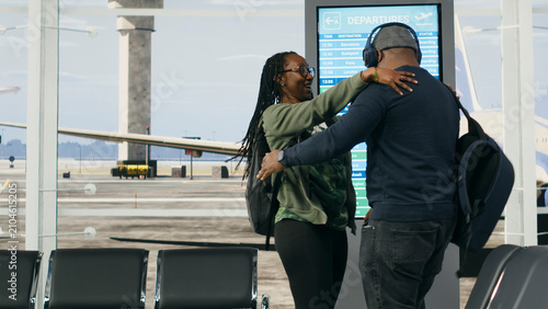 Fotografie Black couple shares an emotional hug upon arriving at the airport, capturing a passionate reunion filled with affection, intimacy and the meaningful feeling of returning home to a loved one