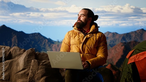 Bild auf Leinwand Hiker works online in nature with a strong mobile signal while climbing a mountain and staying connected to a remote work platform