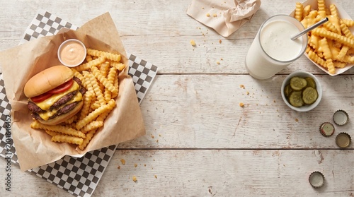 Top view of double cheeseburger and crinkle cut fries on checkered paper, copy space
