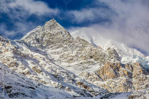 Snowy mountain peak with dramatic clouds, perfect for adventure and nature photography. High quality commercial imagery suitable for marketing, advert
