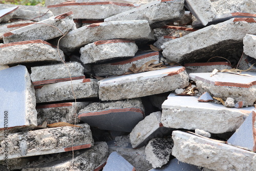 Close-up of cracked reinforced concrete debris piled after demolition at active construction site