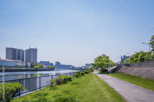青空の下で穏やかに流れる川と緑豊かな遊歩道の景色