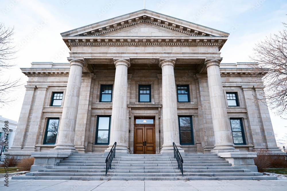 Obraz premium Majestic Neoclassical Architecture Featuring Grand Stone Columns and Staircase Under a Cloudy Sky