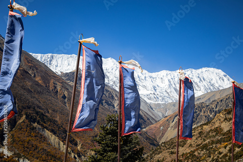 Fotografie Row of blue Tibetan prayer flags waving with snow-capped mountain peak at an alt
