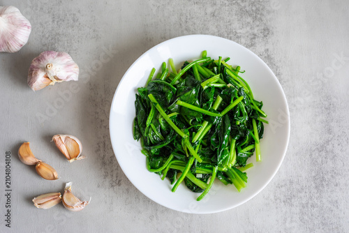 Cuadro en lienzo A plate of lightly sautéed spinach on a dining table