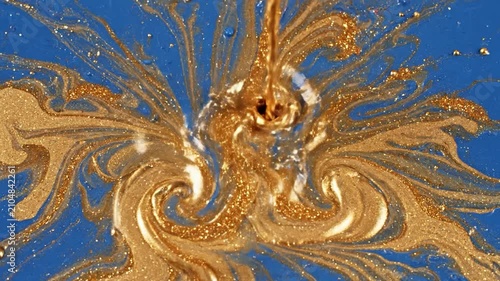 Golden liquid paint splashing on a vibrant blue surface