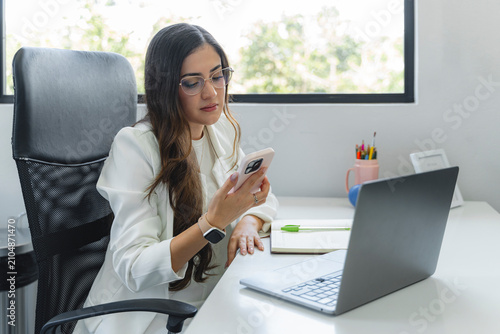 Tableau sur toile Professional concentrating at desk using smartphone and laptop