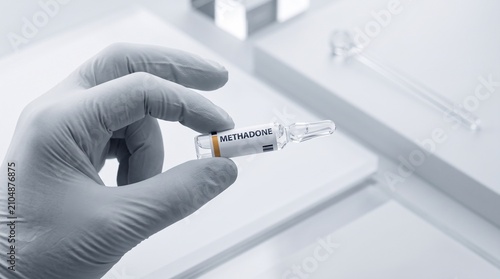 Gloved hand holding methadone medication ampoule for medical treatment or clinical research laboratory analysis with labeled methadone