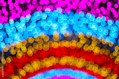 Vibrant rainbow bokeh lights texture in curved lines layout. Blurry round circle neon lighting at night festival celebration background