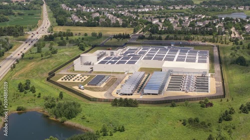 Aerial view of a data center with solar panels on the roof, AI center surrounded by roads and green areas